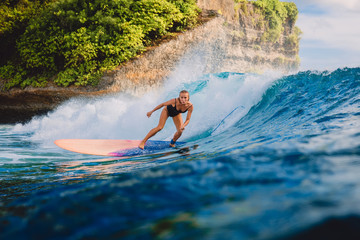 Surfer woman ride on wave surfing. Surfer and ocean wave in Bali