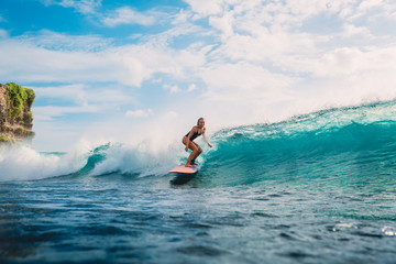 Surfer woman on surfboard during surfing. Surfer and ocean wave - obrazy, fototapety, plakaty