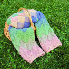 Colorful pink, green, blue, orange, knitted wool cardigan in wooden basket on the green grass...