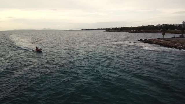 Flying over the sea on a cloudy day. Small island on the horizon.