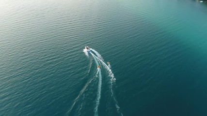 Boat towing water tubes on clear blue lake