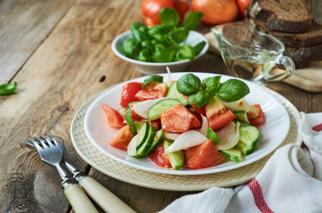 Fresh vegetable salad with ripe tomatoes and cucumbers on a plate