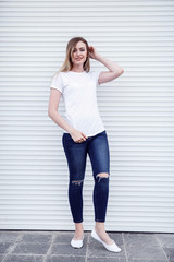Sexy blonde in a white t-shirt is standing on a white background. Mockup.