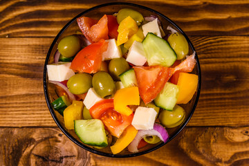 Glass bowl with greek salad on wooden table. Top view