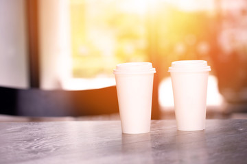 Two hot paper cups of espresso coffee on table in cafe restaurant - with copy space to insert text.