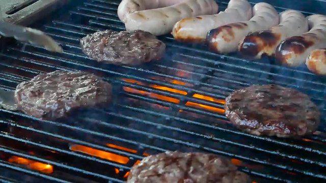 Grilling burgers and sausages on the grill over fire, Manchester UK