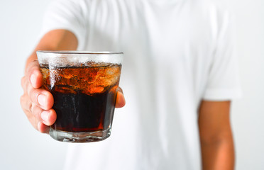 close up man's hand holding a glass of iced cola flavor soda soft drink on white background, copy space, health care concept