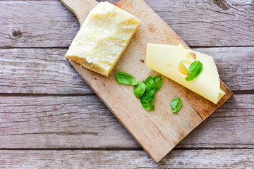 Parmesan and  Maasdam    Emmental-style Dutch cheese and fresh basil on wooden board