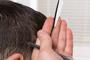 cutting short hair on the child's head with scissors and combs, close-up