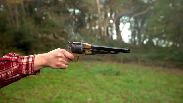 Revolver gun appears in shot to fire off round, smoke, black powder, bang, close-up