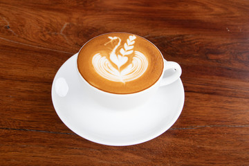 coffee cup latte art on wooden table.hot drink coffee with milk froth for breakfast.heart shape art foam texture top view.