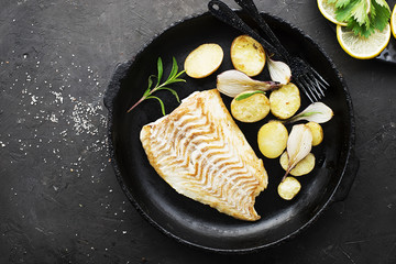 Cod fillet baked with fresh farmer's vegetables: potatoes, carrots, onions. Top View,