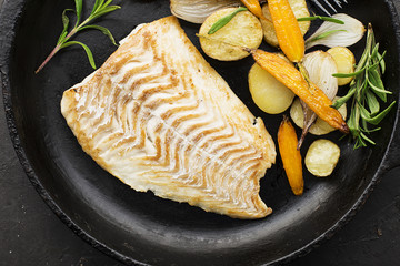 Cod fillet baked with fresh farmer's vegetables: potatoes, carrots, onions. Top View,