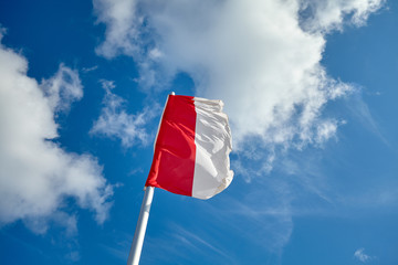 Polish flag against blue sky on a sunny day.