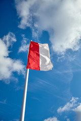 Polish flag against blue sky on a sunny day.