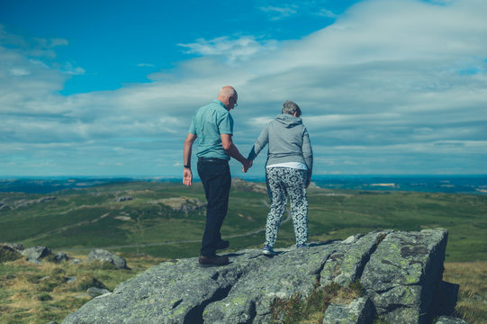 Senior couple standing on rock in the moor