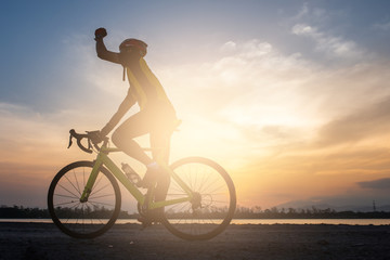 Obraz premium A cyclist hand up and riding a road bike on road in the morning