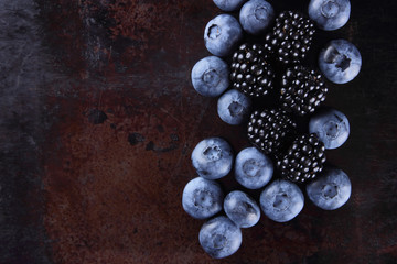 Blueberries and blackberries on a dark background, fresh berries for a vegan, fruits on a rusty...