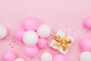 Gift or present box, balloons and confetti on pink pastel table top view. Flat lay composition for birthday or Mothers day.
