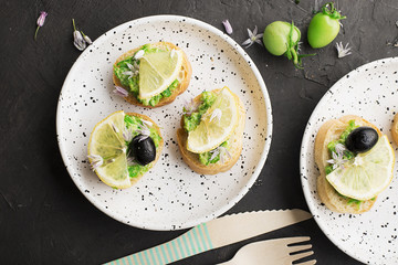 Pesto toast with homemade sauce of garden farming herbs and spices with lemon and olives on a dark background. Top View.