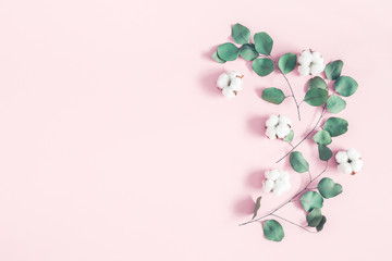 Flowers composition. Eucalyptus leaves and cotton flowers on pastel pink background. Flat lay, top view, copy space