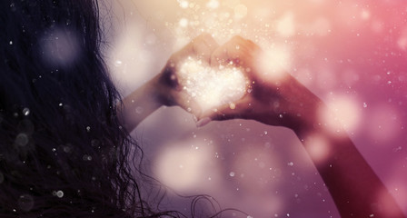 Magic emanating from the hands of a woman, a light effect in the form of hearts in the hands, glare of light, bokeh