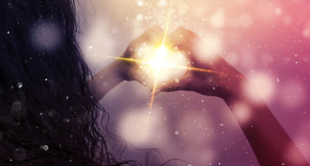 Magic emanating from the hands of a woman, a light effect in the form of hearts in the hands, glare...