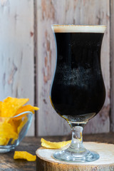 A glass of cold dark beer on wooden table - closeup with selective focus