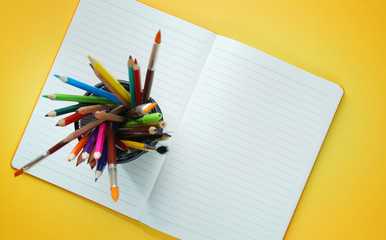 School Stationary in Basket on Opened Book Top View Yellow Background