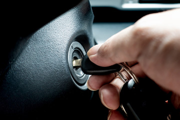 Hand turning car key in the key hole to start the car engine - 216779384