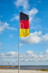 German flag on a pole against the sky on a sunny day.