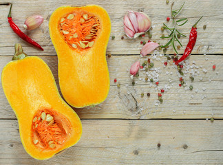 The halves of the pumpkins. Raw organic butternut squash with ingredients for cooking on a wooden table. 