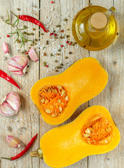 Raw organic butternut squash with ingredients for cooking on a wooden table. Selective focus