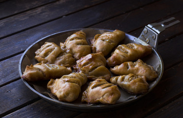 Tasty little pies in a pan on a dark wooden background. Homemade cake.