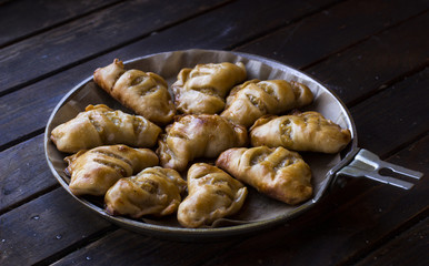 Delicious little pies in a pan on a dark wooden background. Homemade cake.