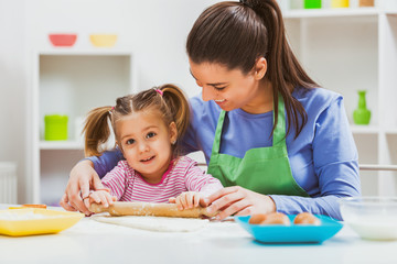 Happy mother and daughter are making cookies in their kitchen. 