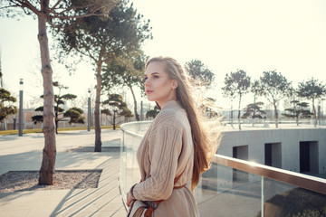 A young gorgeous woman on a walk through the sunny winter park.