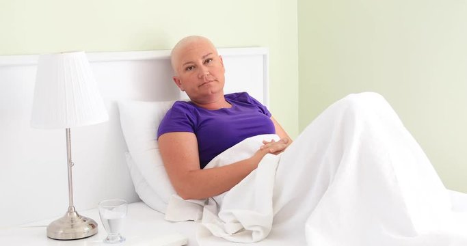 Female cancer patient laying in bed and looking at the camera