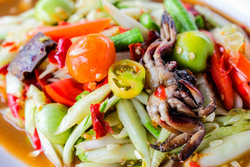 Som Tam (Spicy Papaya Salad) with salted crab, on wooden table ( Thai food)