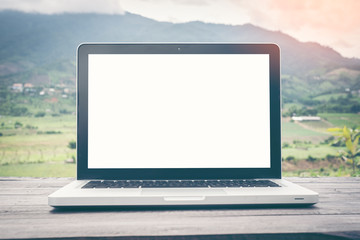 Blank screen Laptop on wood table top at blur background of mountain. For Graphic display or montage your products.