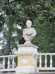 Obraz premium White statue on a park fence against a background of green trees