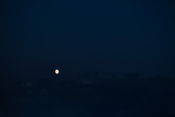 three-quarters of the growing moon on the navy blue sky background  with some visible clouds in mystic mood