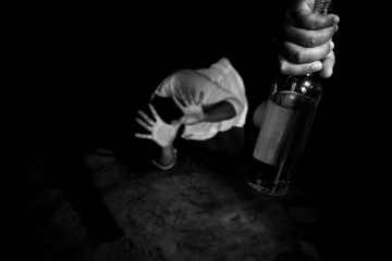 Woman victim of domestic violence and abuse. Woman scared of a man holding alcohol bottle. - obrazy, fototapety, plakaty
