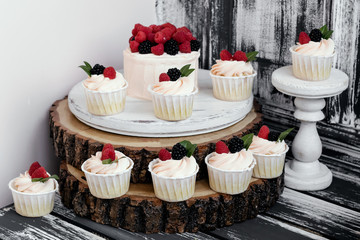 Festive Cake and muffins with raspberries and blackberries on wooden background.