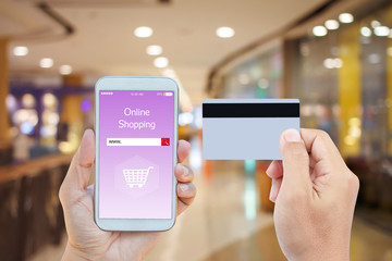 Hand holding smart phone with online shopping on screen and credit card over blurred in shopping mall background for mobile banking payment online concept