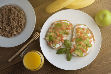 Homemade Healthy Toast sandwich with Avocado, cheese cream and tomatoe. Glass of fresh juice and fruits, on wooden board. Breakfast healthy food.