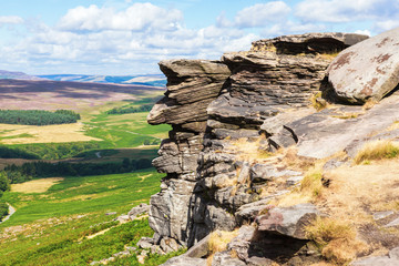 Peak District National Park, Derbyshire, England. Rock formations in Stanage edge, with the fields and pastures on the background, selective focus