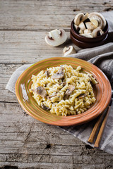 Italian pasta fusili with mushrooms and cream sauce on wooden table, copy space, top view. Autumn Food Concept