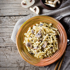 Italian pasta fusili with mushrooms and cream sauce on wooden table, copy space, top view. Autumn Food Concept