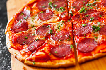 sliced Pepperoni Pizza with Mozzarella cheese, salami, Tomatoes, pepper, Spices and Fresh Basil. Italian pizza